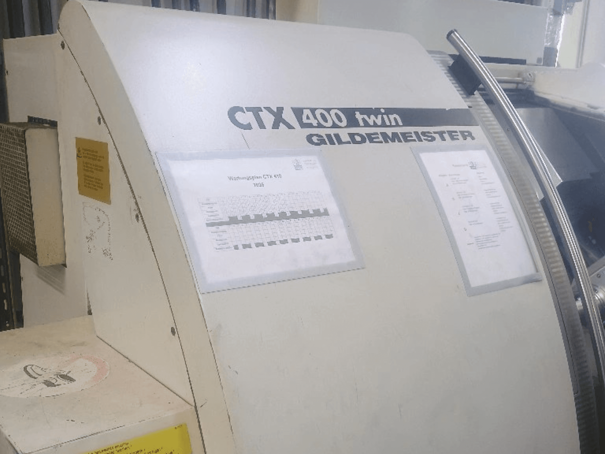 Dvostruki horizontalni tokarski stroj Gildemeister CTX 400, pogled sprijeda, s prikazom operativnih ploča i tehničke dokumentacije.