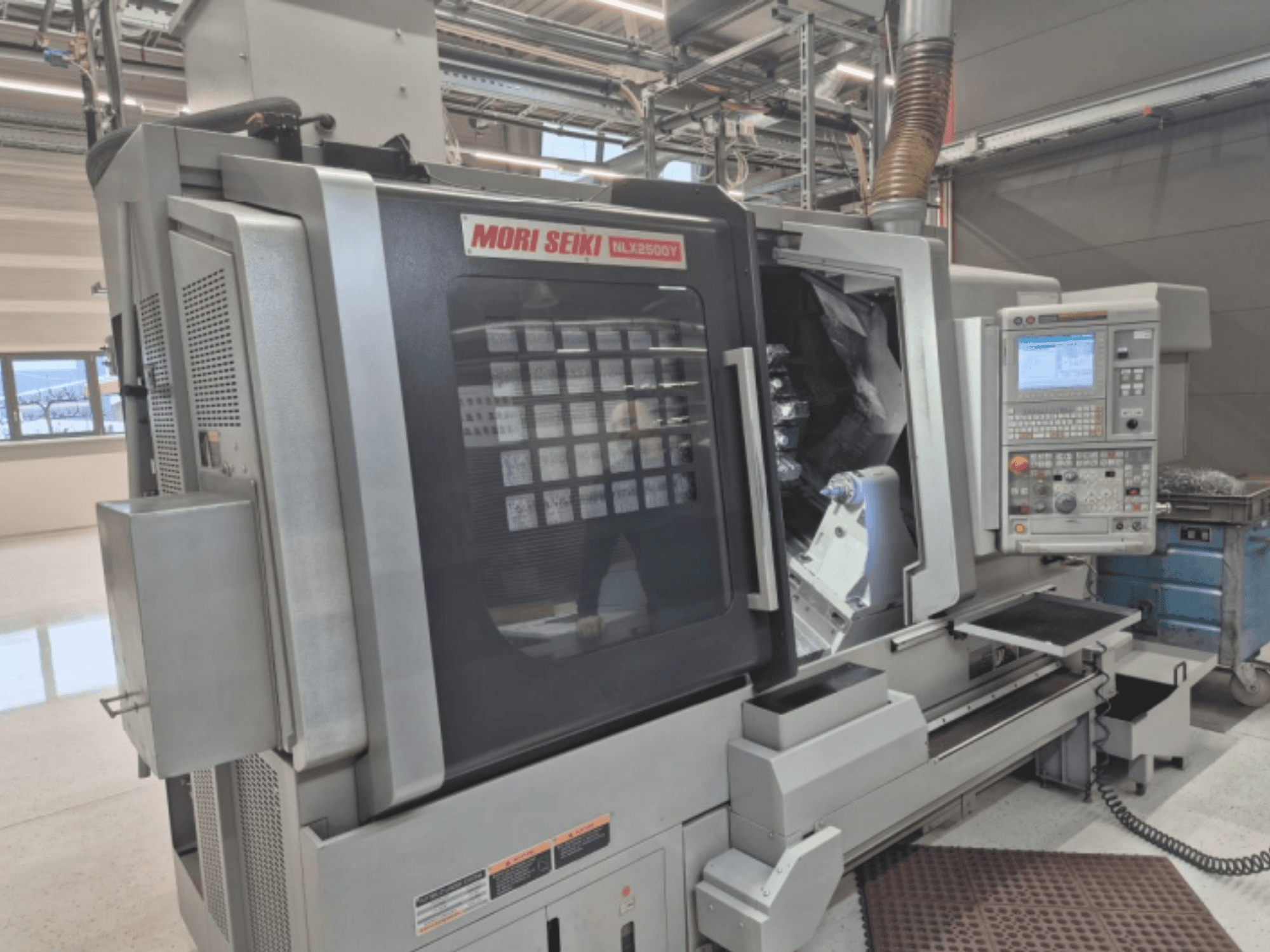 MORI SEIKI NL2500Y CNC tokarski stroj u tvorničkom okruženju, prednji pogled s prikazom upravljačke ploče i komore za obradak.