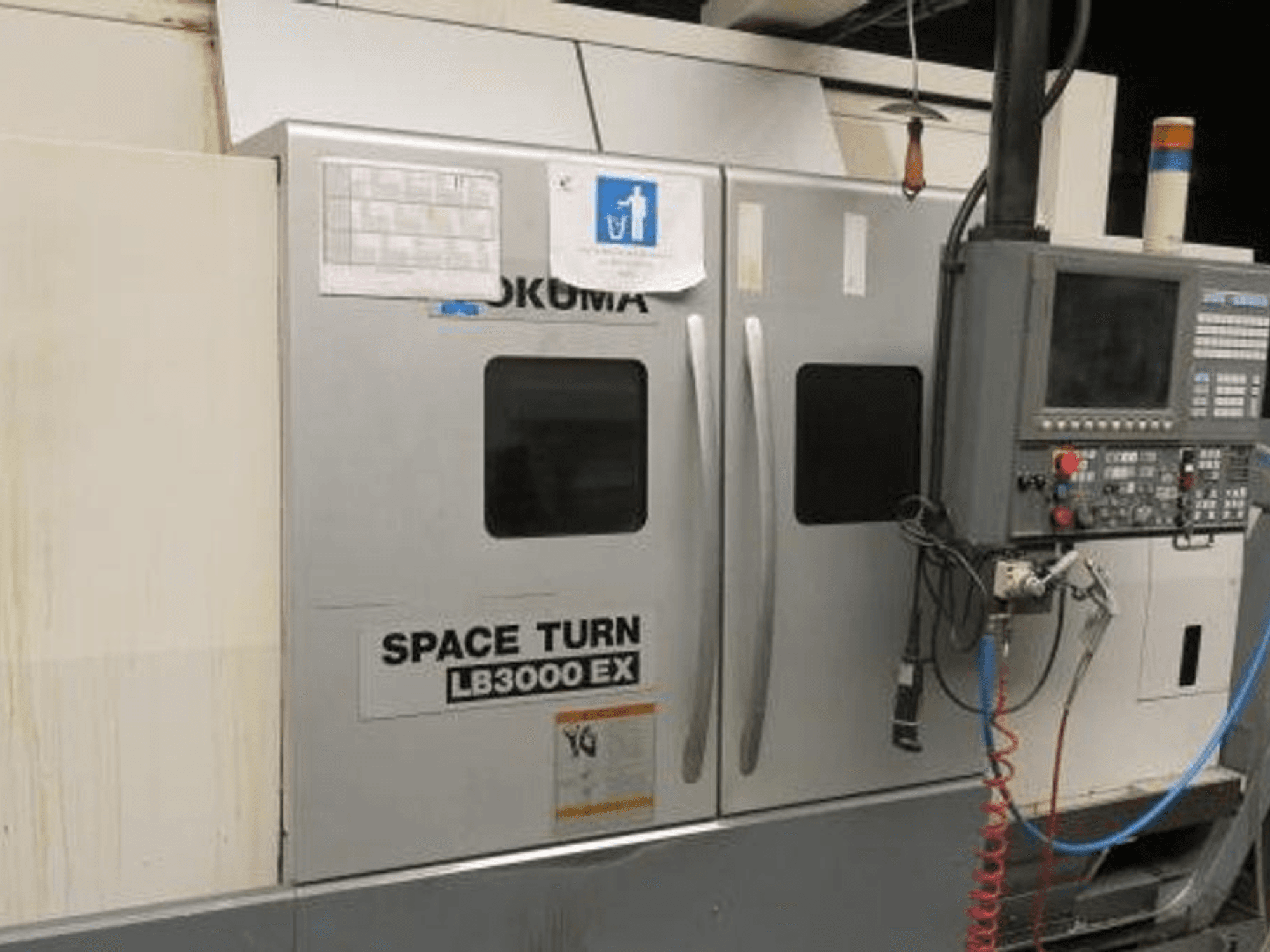 Okuma Space Turn LB3000 EX CNC tokarski stroj, bočni pogled, s upravljačkom pločom, dvoja vrata i vidljivim ožičenjem.