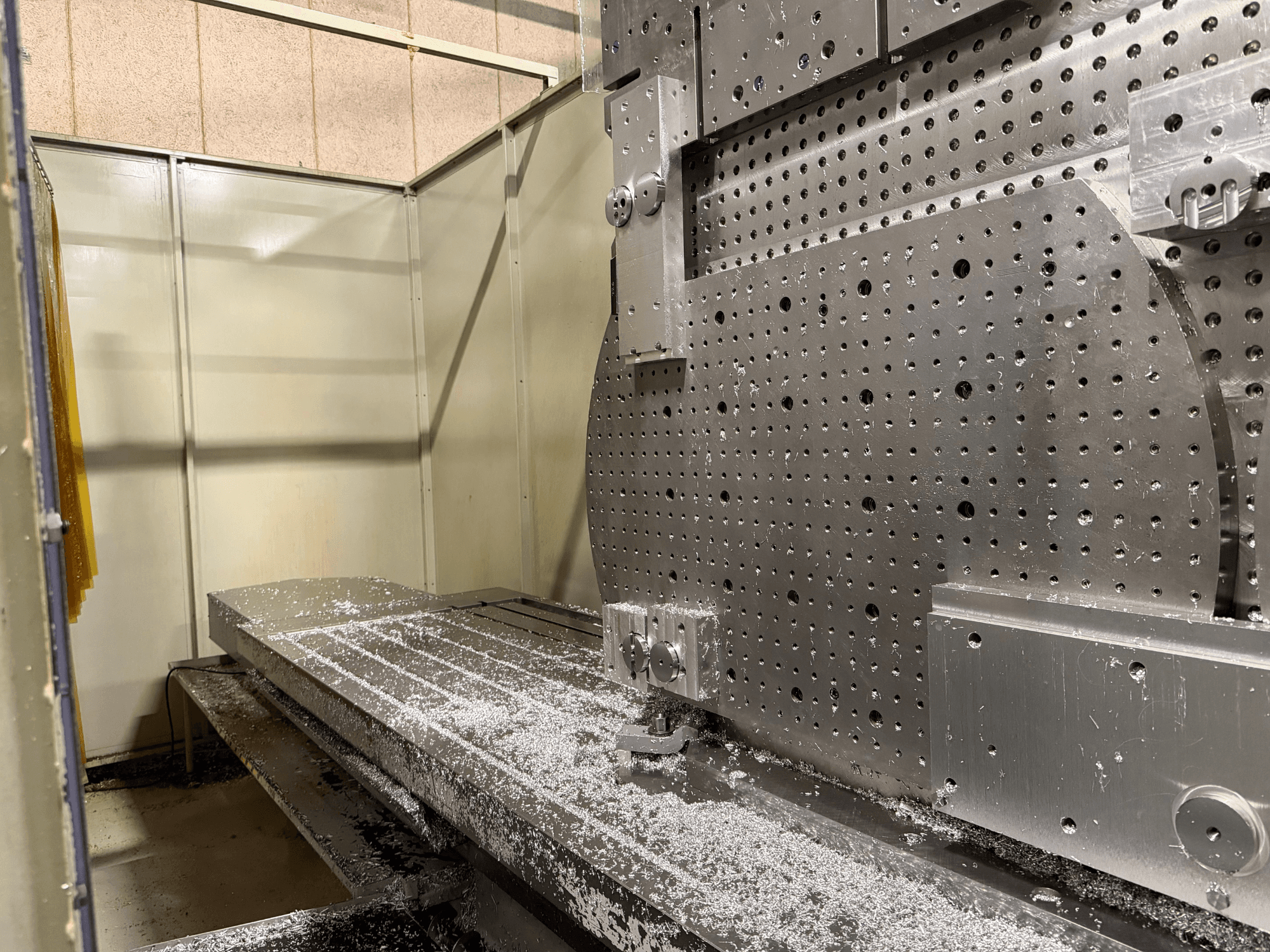 Pogled izbliza na prednju stranu univerzalnog obradnog centra KIHEUNG KNC-U1000, koji prikazuje metalni radni stol s aluminijskim strugotinama.